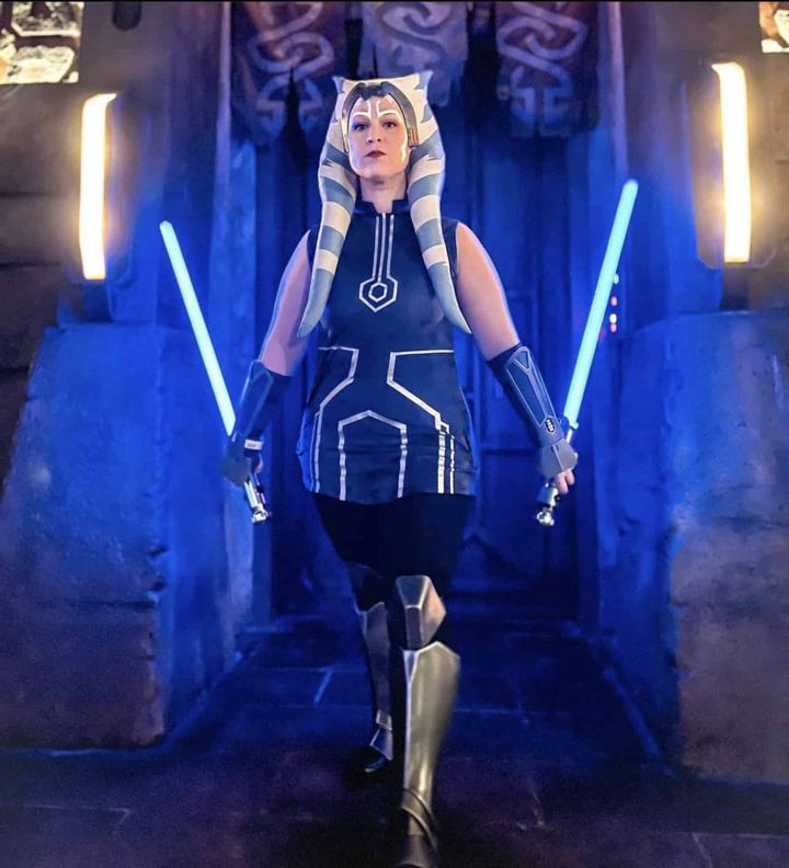 Ahsoka Tano cosplayer in a custom live-action headpiece, lit by two blue lightsabers